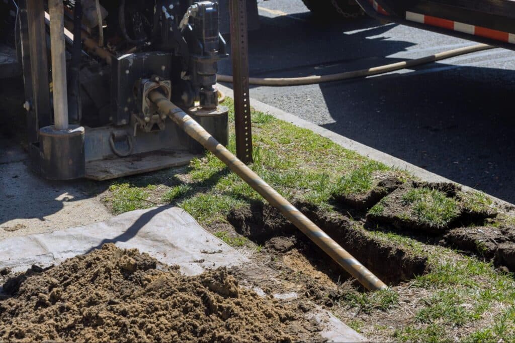 plumbing services taking place with underground drilling machinery operating on a site with freshly dug earth.