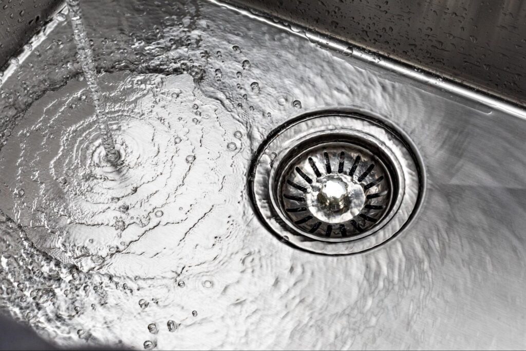 Water flowing smoothly into a kitchen sink drain.