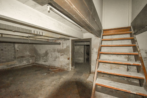 Dimly lit basement stairs leading to a cluttered underground space.