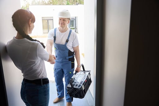 Homeowner shaking hands with contractor, discussing home improvement project at the doorstep.