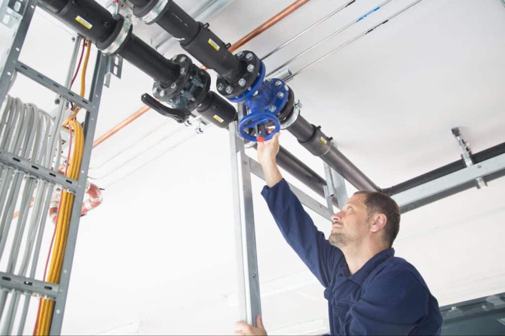 Worker adjusting a valve on industrial piping in a modern facility.