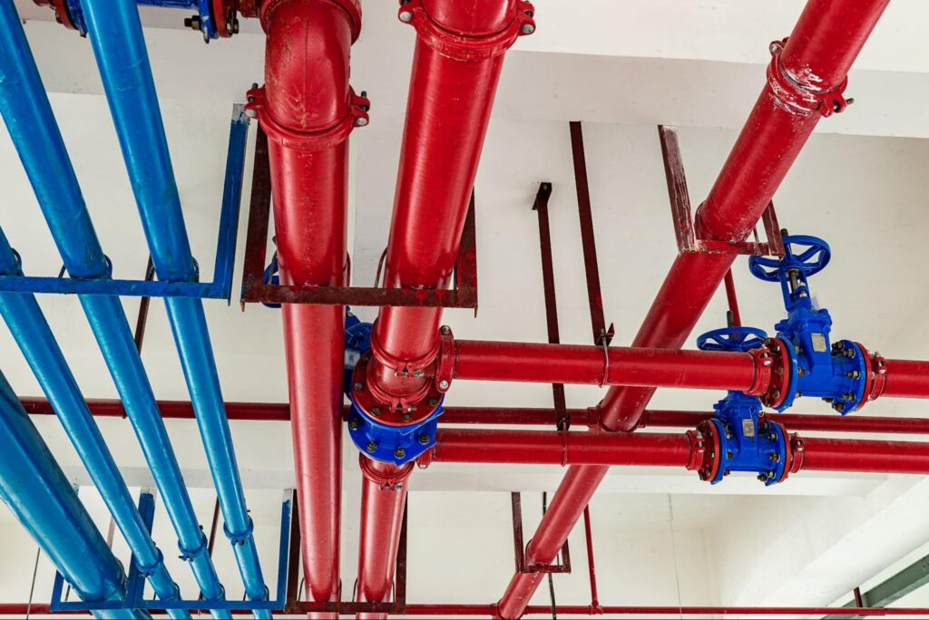 Colorful overhead industrial pipes and valves in blue and red configuration.