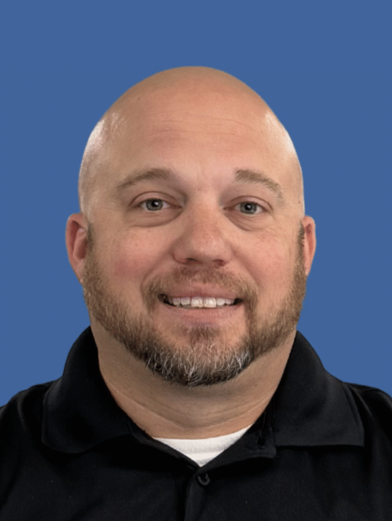Professional headshot of a smiling man in a black shirt against a blue background.