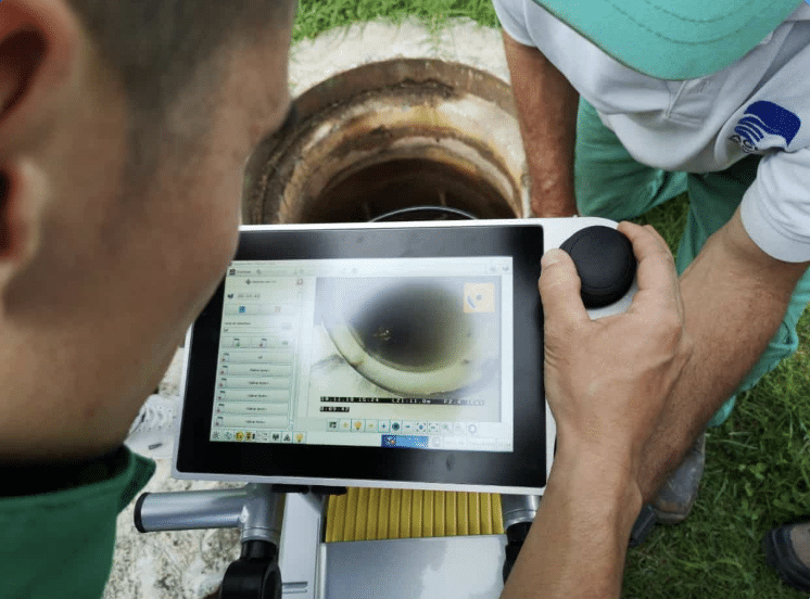 Technician using tablet to inspect sewer pipe conditions for trenchless pipe installation.