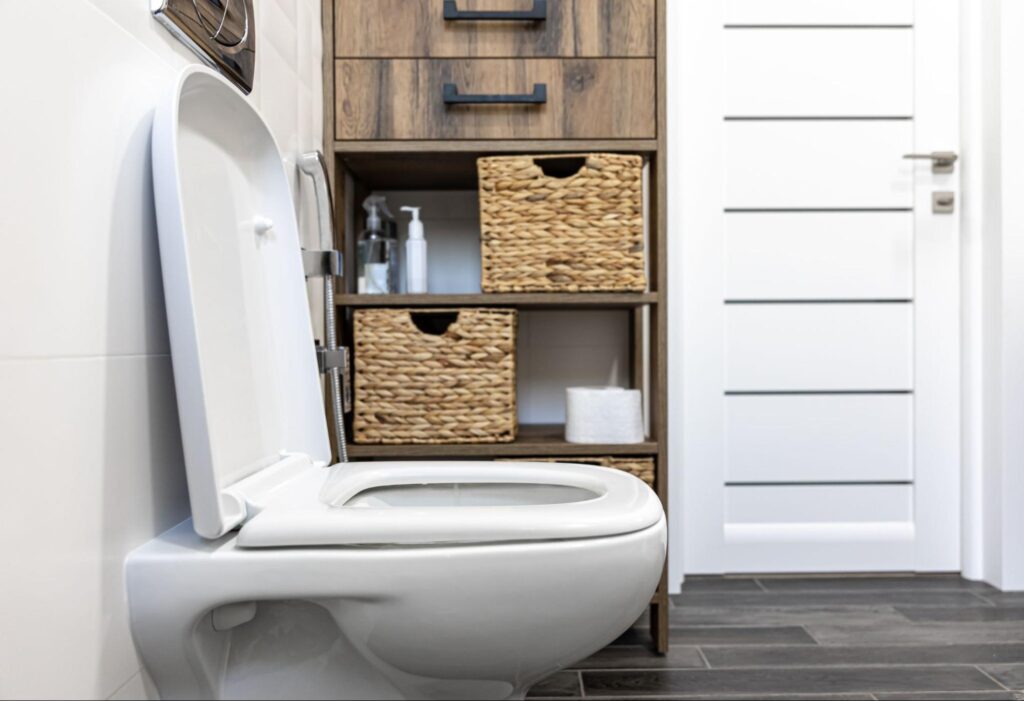 Modern bathroom with sleek toilet, wooden storage, and minimalist design elements.