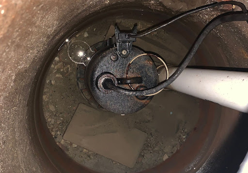 Rusty pump mechanism submerged in water, showcasing plumbing installation details.