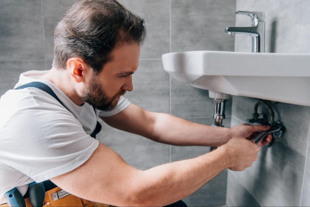 Professional plumber repairing a bathroom sink during home renovation.