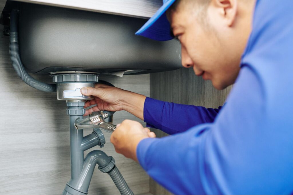 Plumber repairing sink drain with wrench for efficient plumbing solutions.