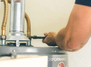 Technician repairing a water heater with a wrench for optimal performance.