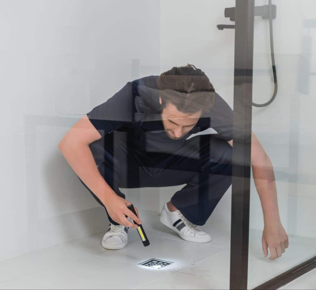 Inspecting hidden details with a flashlight in a bathroom space.