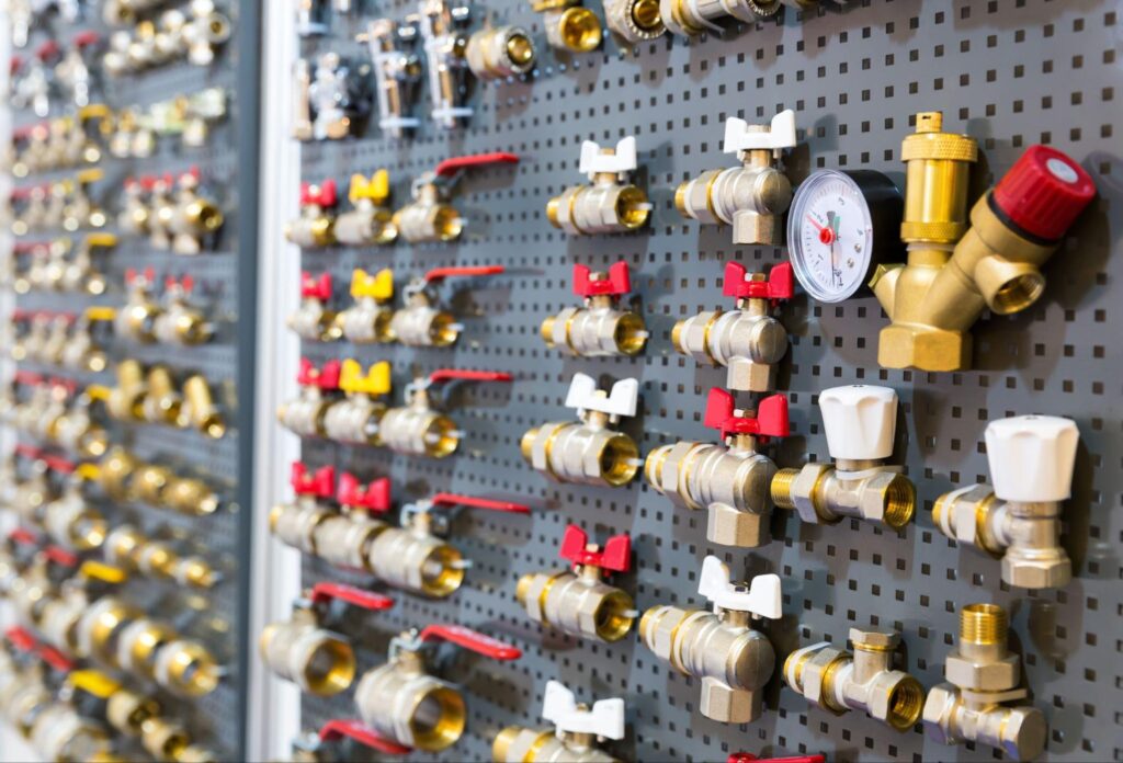 Variety of plumbing valves and fittings displayed on a pegboard wall.