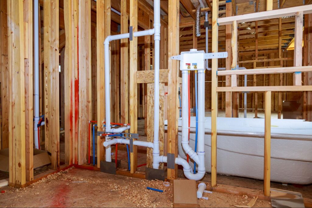 Plumbing installation in a construction site showcasing PVC pipes and framing structures.