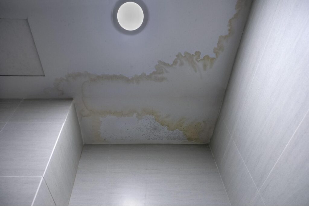 Ceiling water damage with stains in a bathroom, needing repair and restoration.