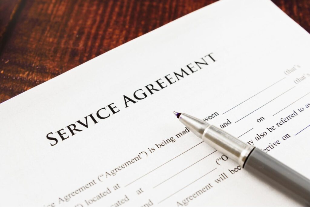 Service agreement document with a silver pen on a wooden surface.