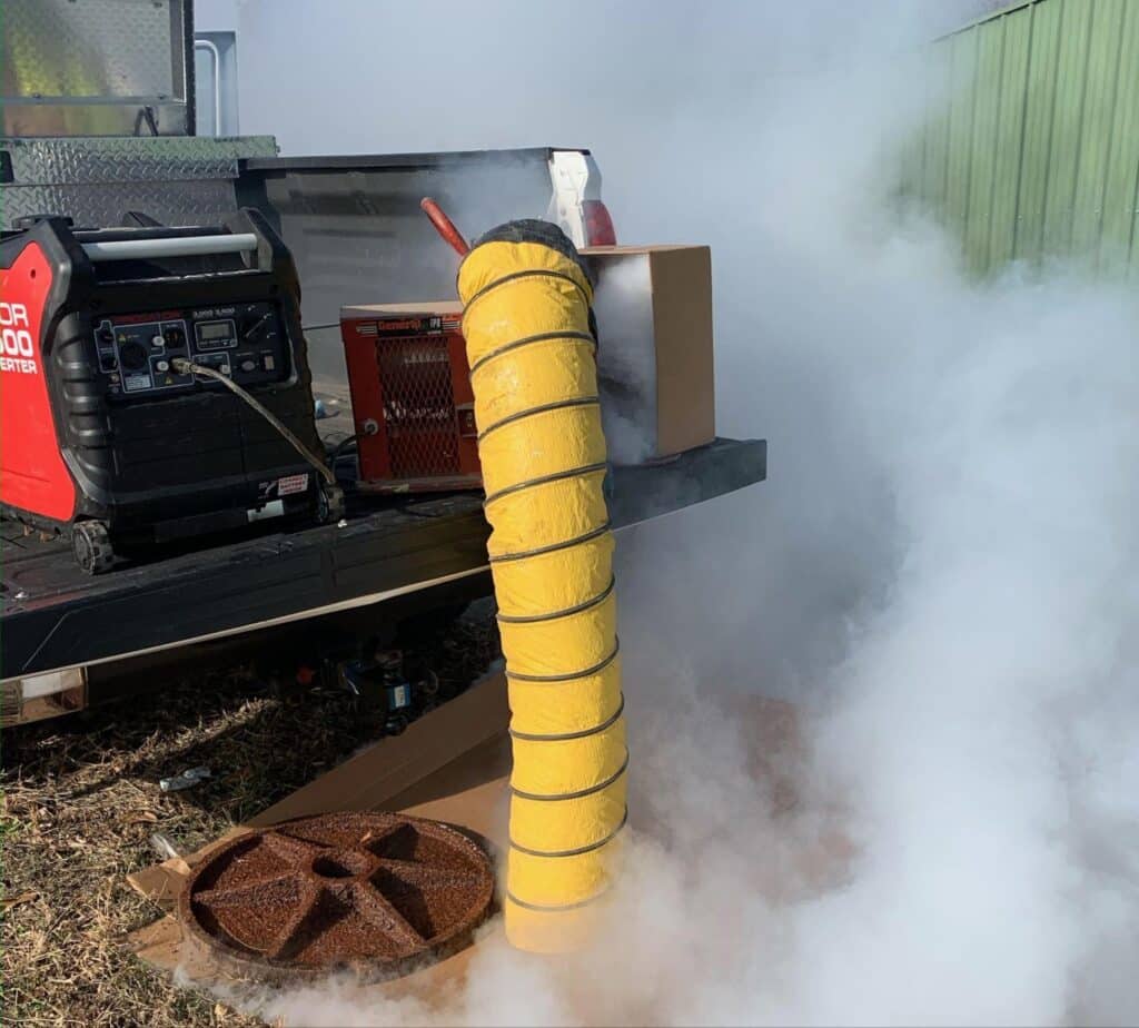 Generator with yellow exhaust pipe releasing smoke in outdoor setting.