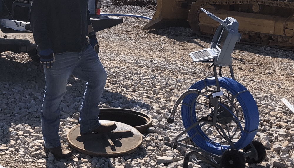 Technician using advanced inspection equipment to examine manhole systems.
