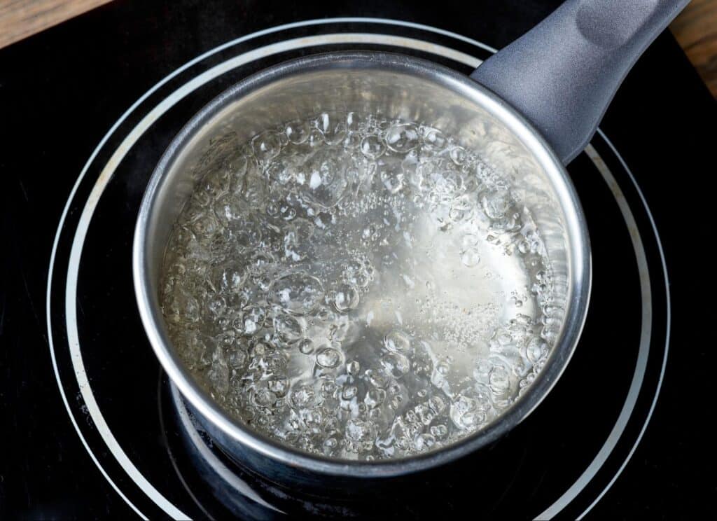 Boiling water in a stainless steel pot on an electric stove.