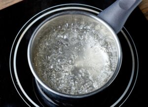 Boiling water in a stainless steel pot on an electric stove.