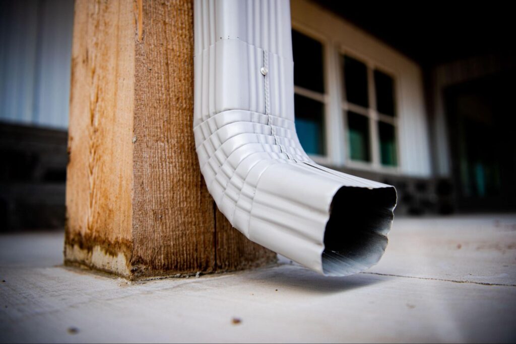 Gutter downspout on wood post efficiently channels rainwater away from the building.