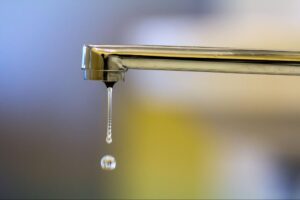 Water dripping from a leaky faucet, highlighting waste and potential water conservation issues.