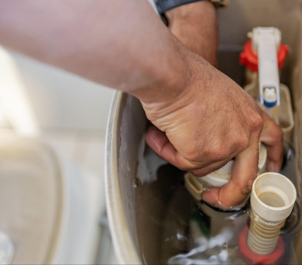 Repairing a toilet tank by adjusting the flush mechanism and checking parts.