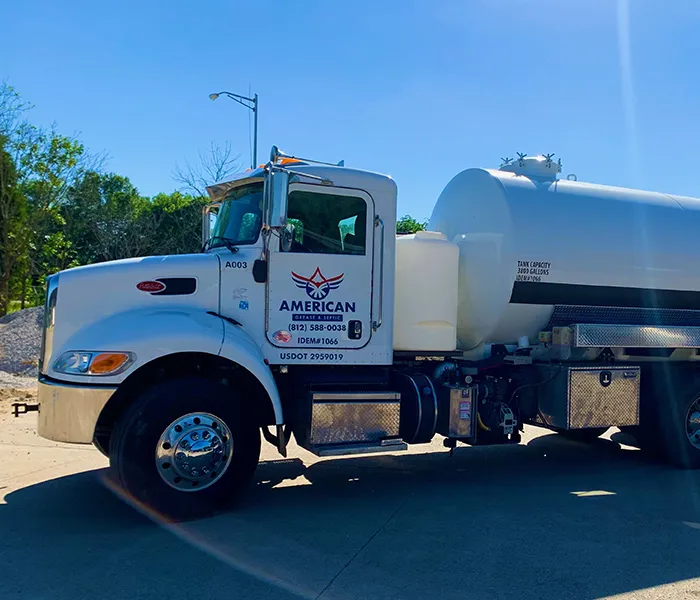 A white water tanker truck parked on a sunny day, displaying company branding. The truck appears sturdy, with trees and a clear sky in the background.